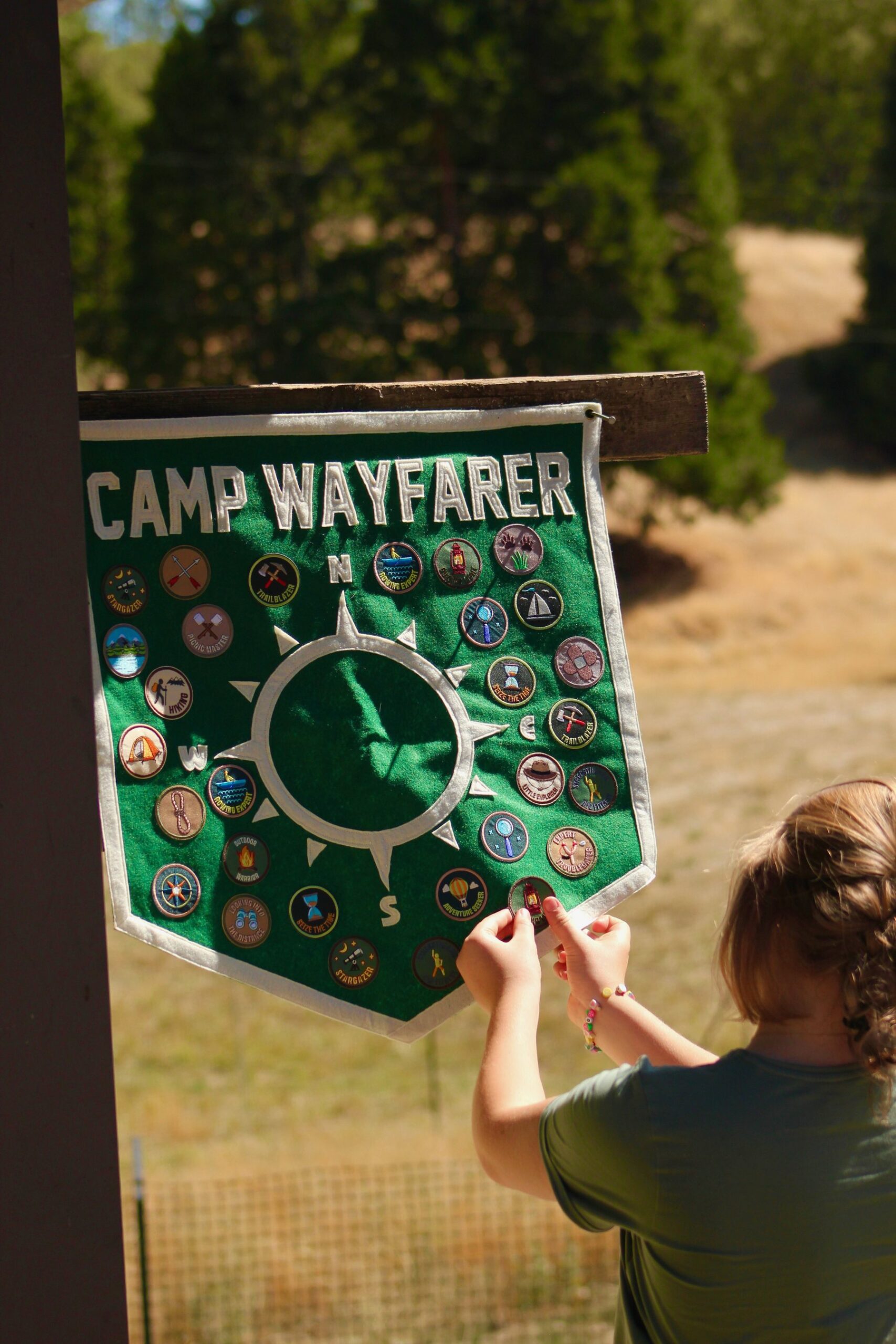 Camper adding award patches to a Camp Wayfarer felt pennant