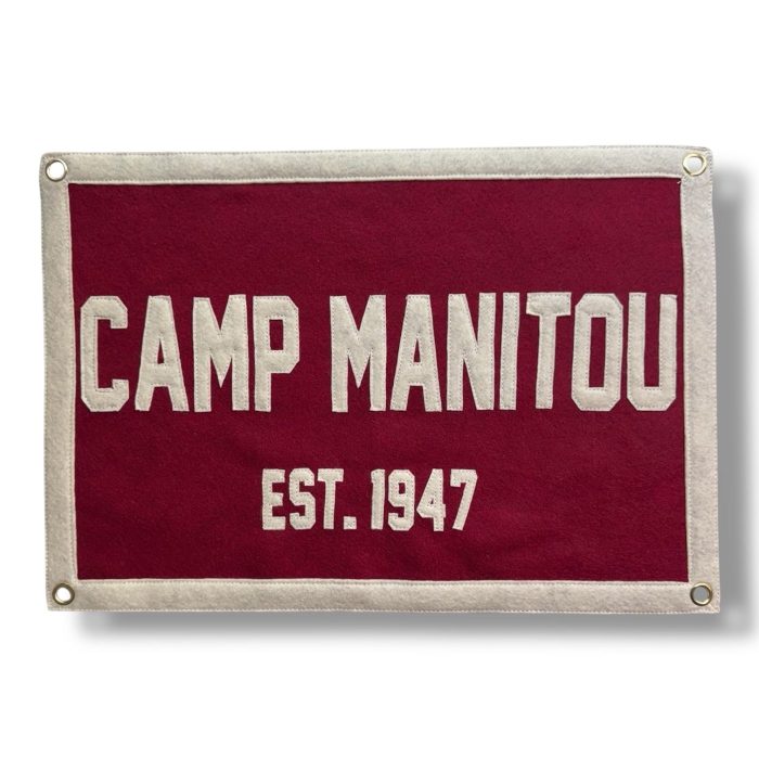 Maroon felt banner reading Camp Manitou Est. 1947 in cream lettering