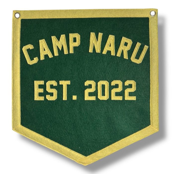 Green felt banner with yellow trim reading Camp Naru Est. 2022