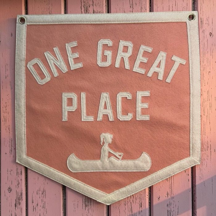 Coral felt camp banner reading One Great Place with a cream felt canoe design
