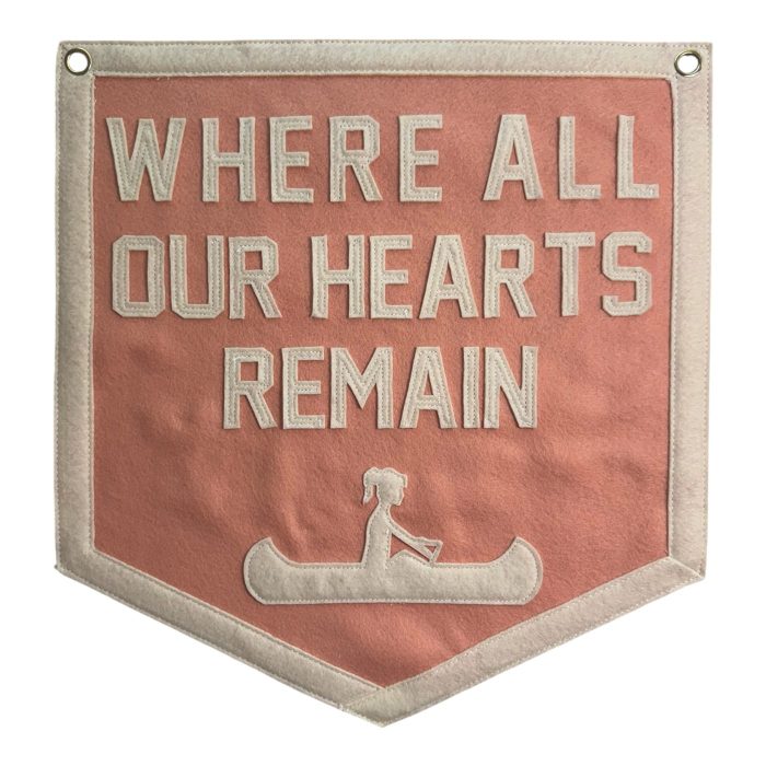 Coral felt banner reading Where All Our Hearts Remain with a cream canoe